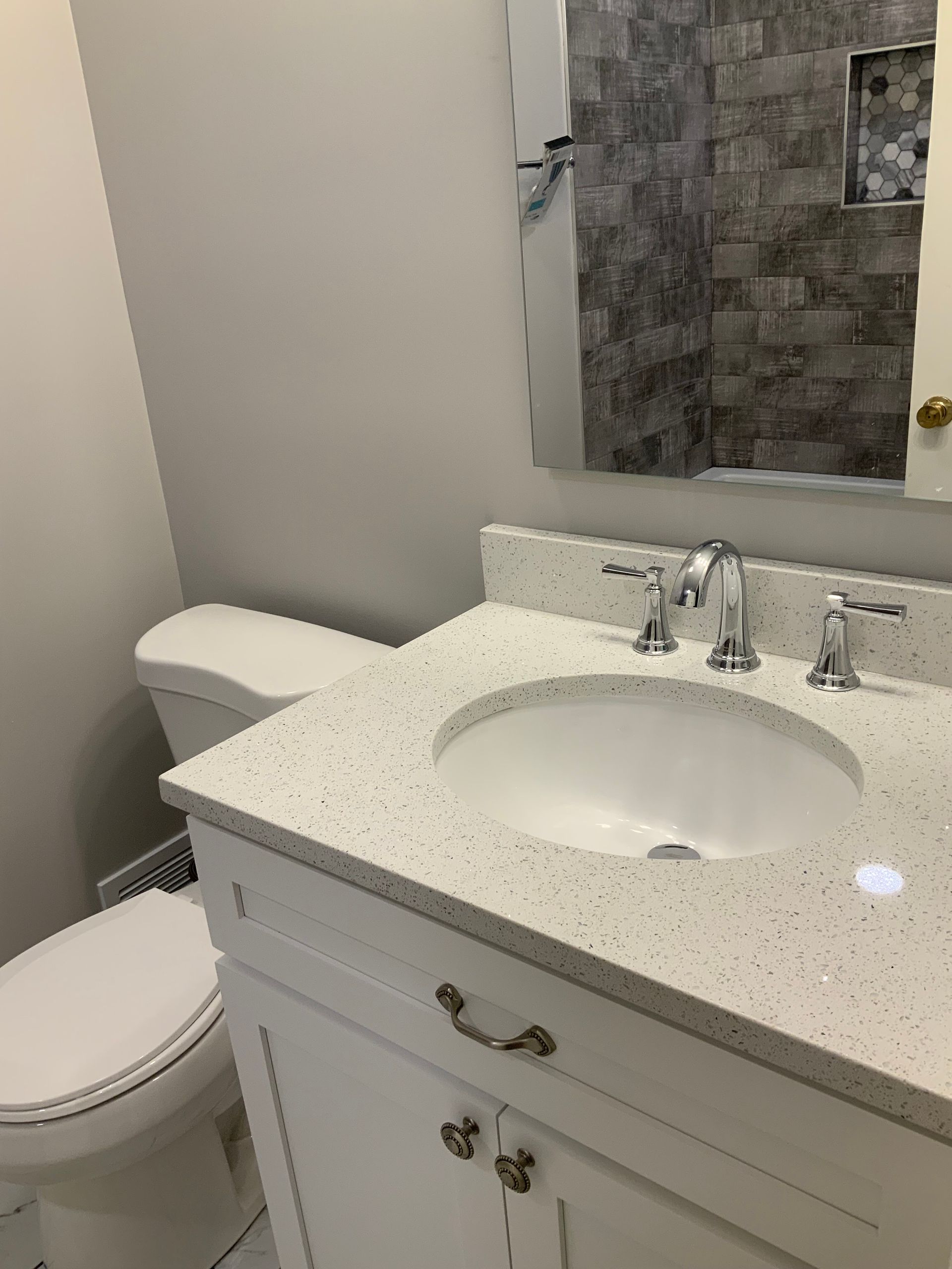 A bathroom with a toilet , sink and mirror