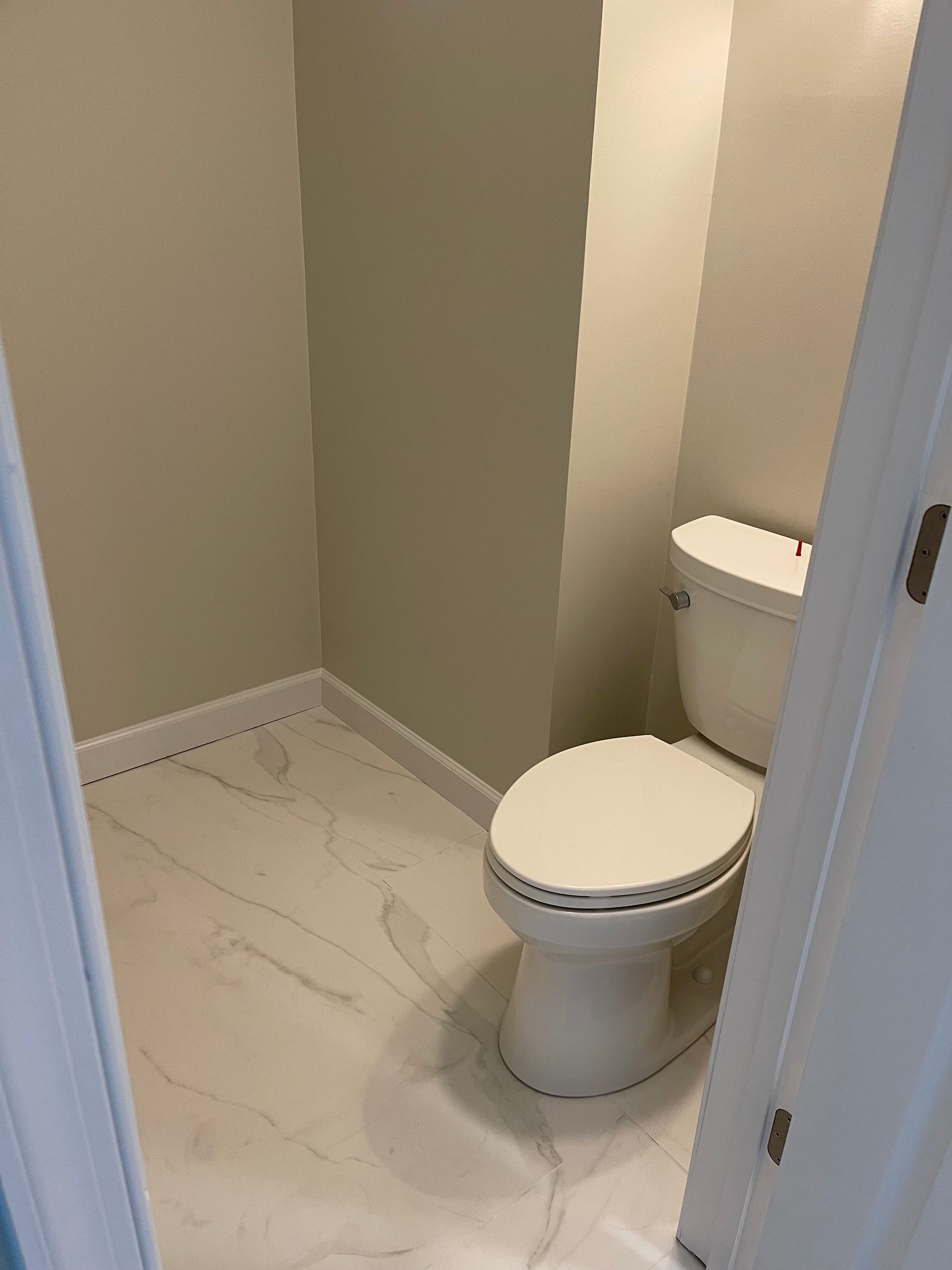 A toilet is sitting in a small bathroom next to a door.