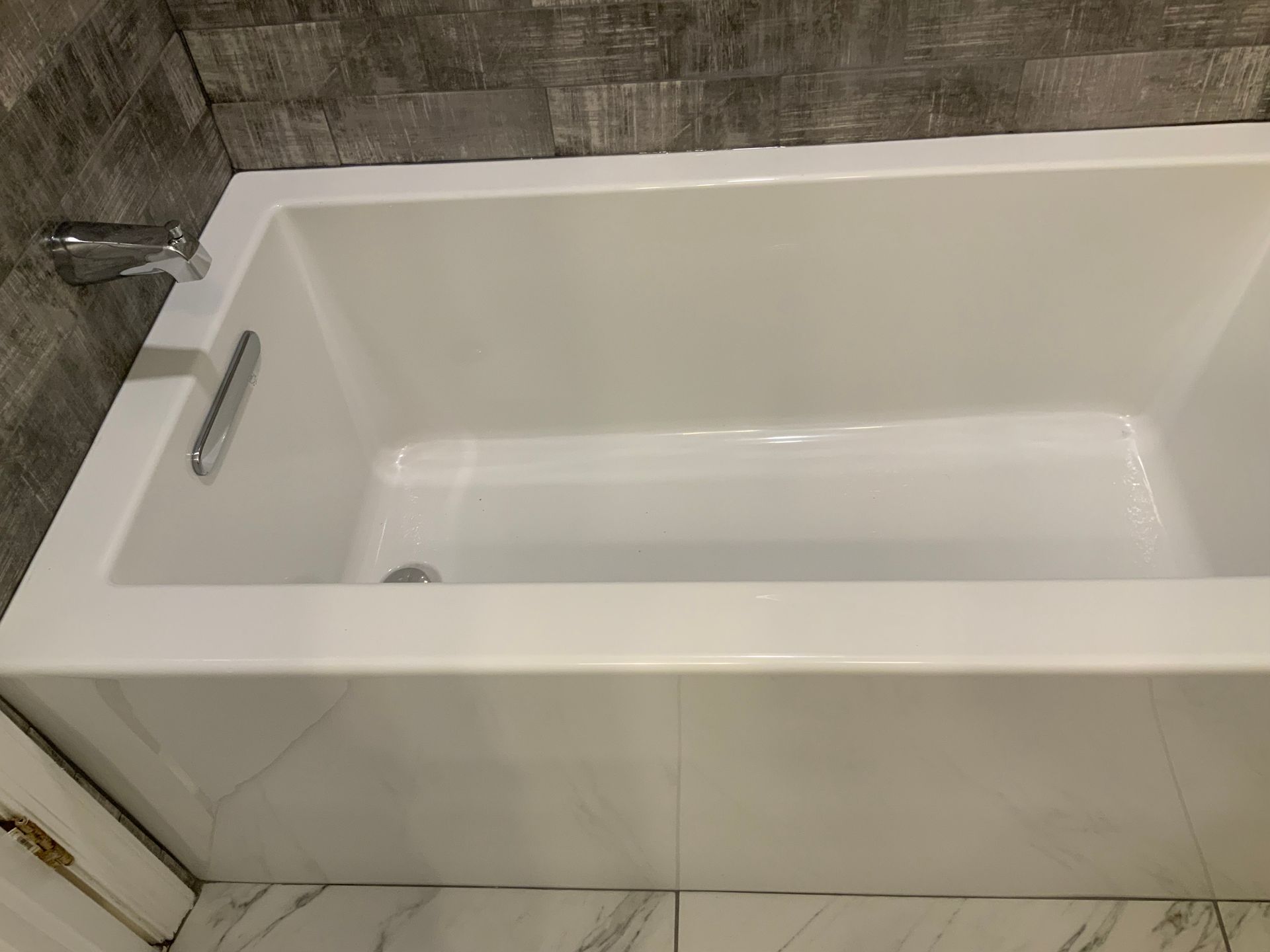 A white bathtub is sitting in a bathroom next to a door.