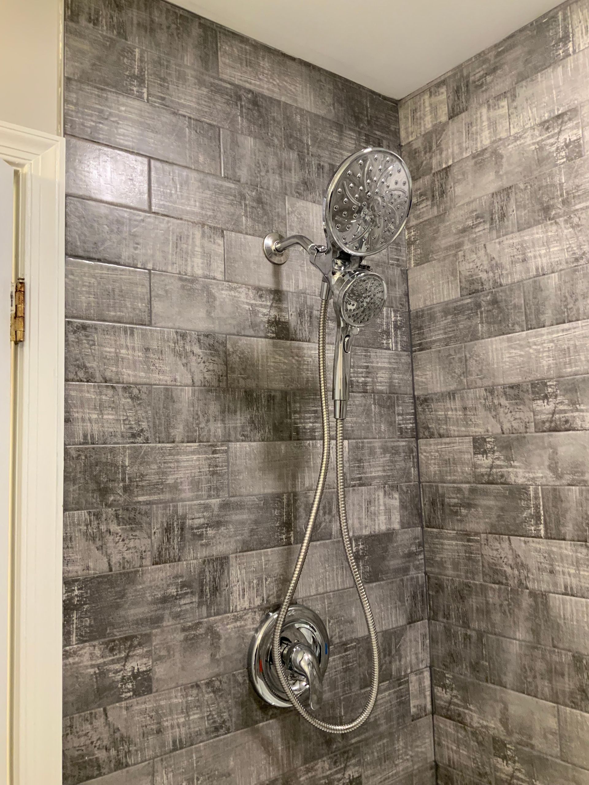 A shower head is hanging from a tiled wall in a bathroom.