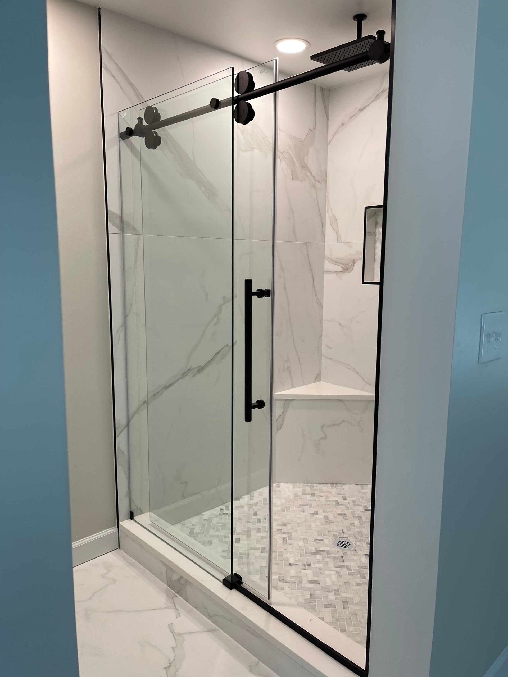 A bathroom with a sliding glass shower door and a black handle.