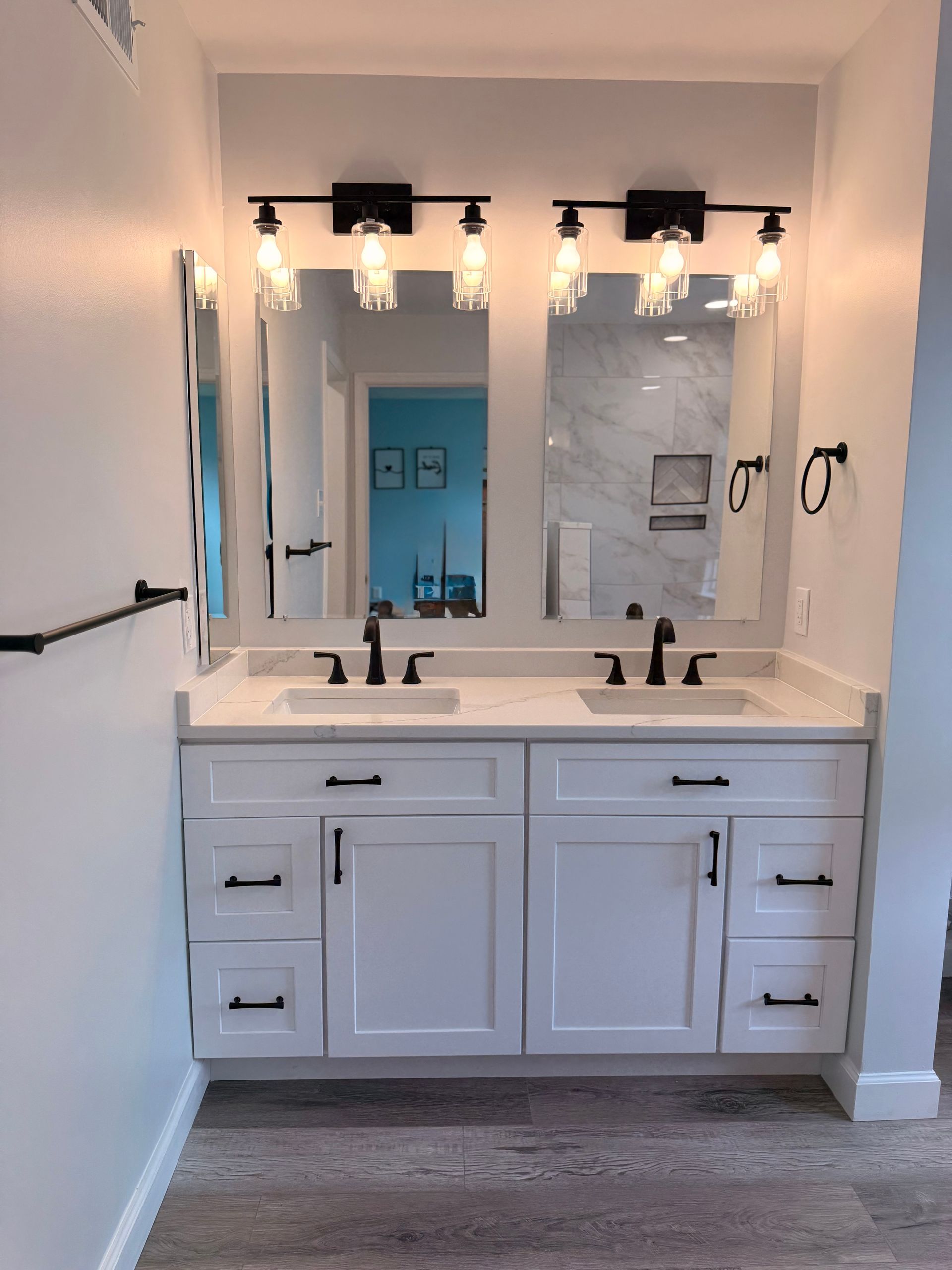 Modern bathroom vanity with double sinks, large mirrors, and wall-mounted lights in a white interior