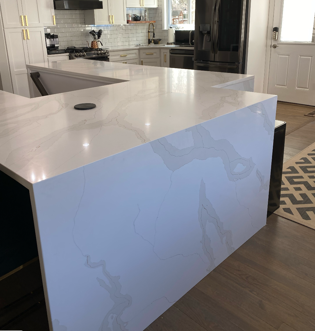 White quartz kitchen island with waterfall sides in a modern kitchen with dark wood floors.