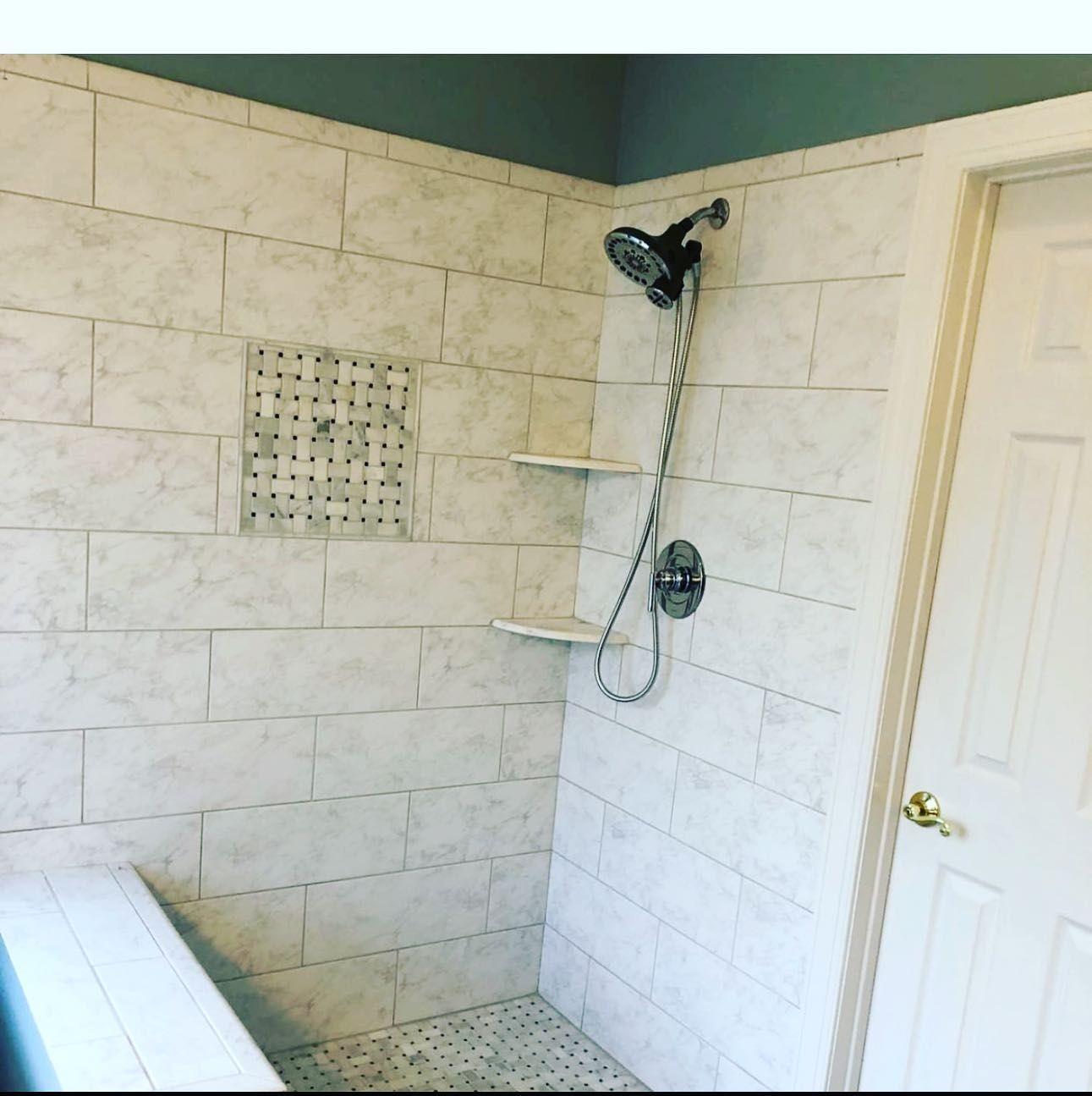 A shower with white tiles and a shower head