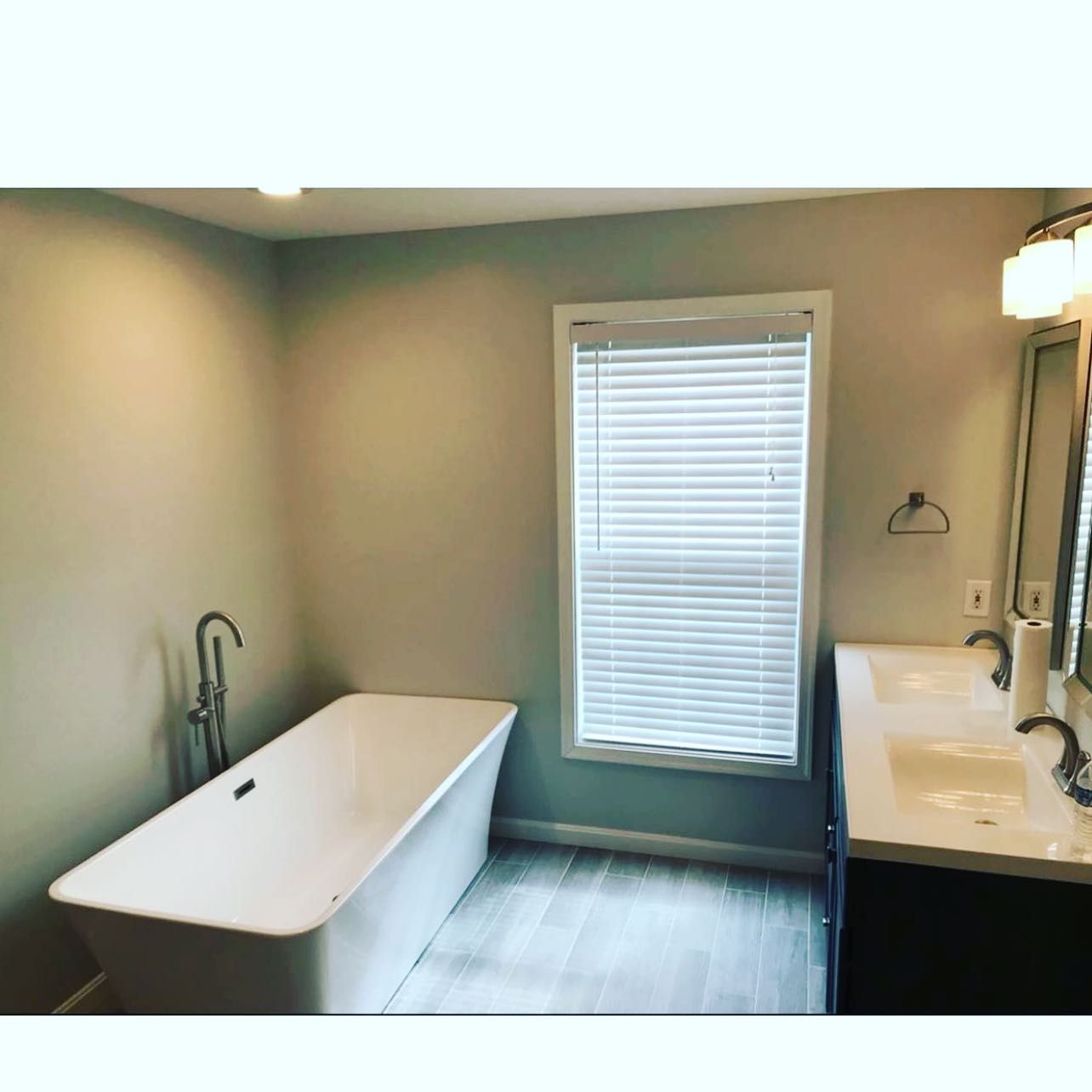 A bathroom with a bathtub , sinks , and a window.