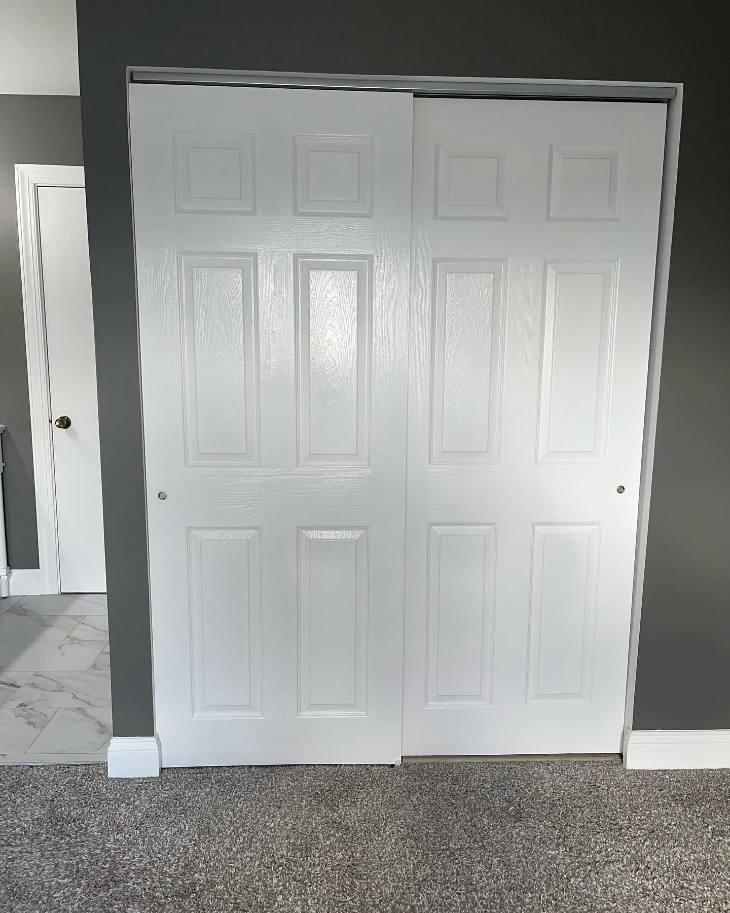 A white closet door is open in a room with a carpeted floor.