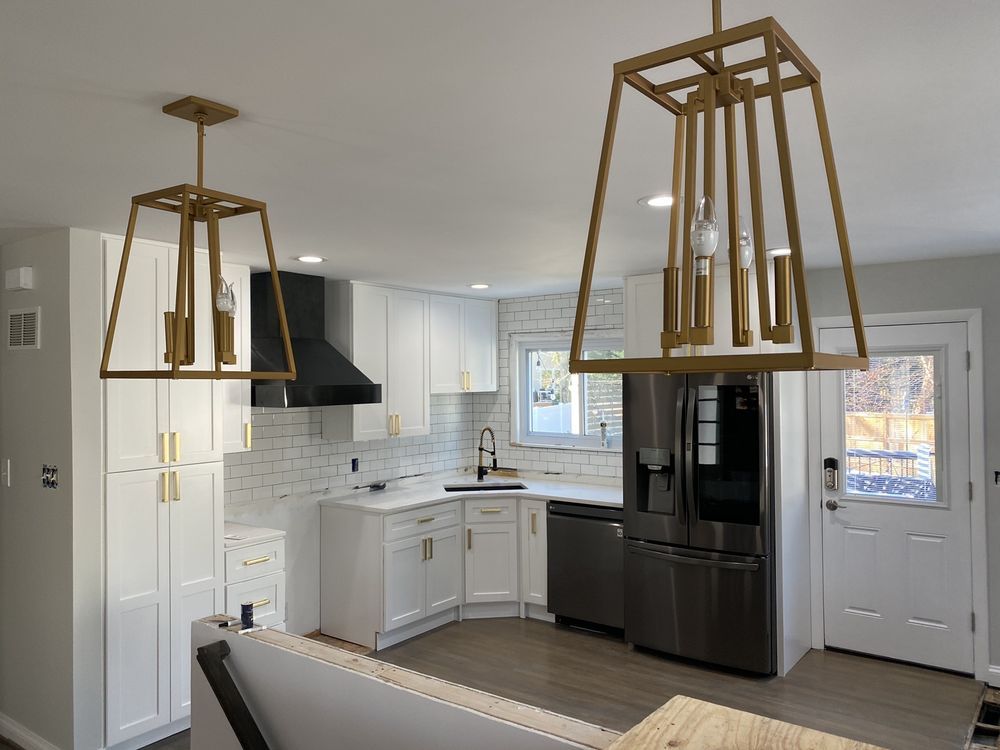 A kitchen with white cabinets , stainless steel appliances , a refrigerator and a sink.