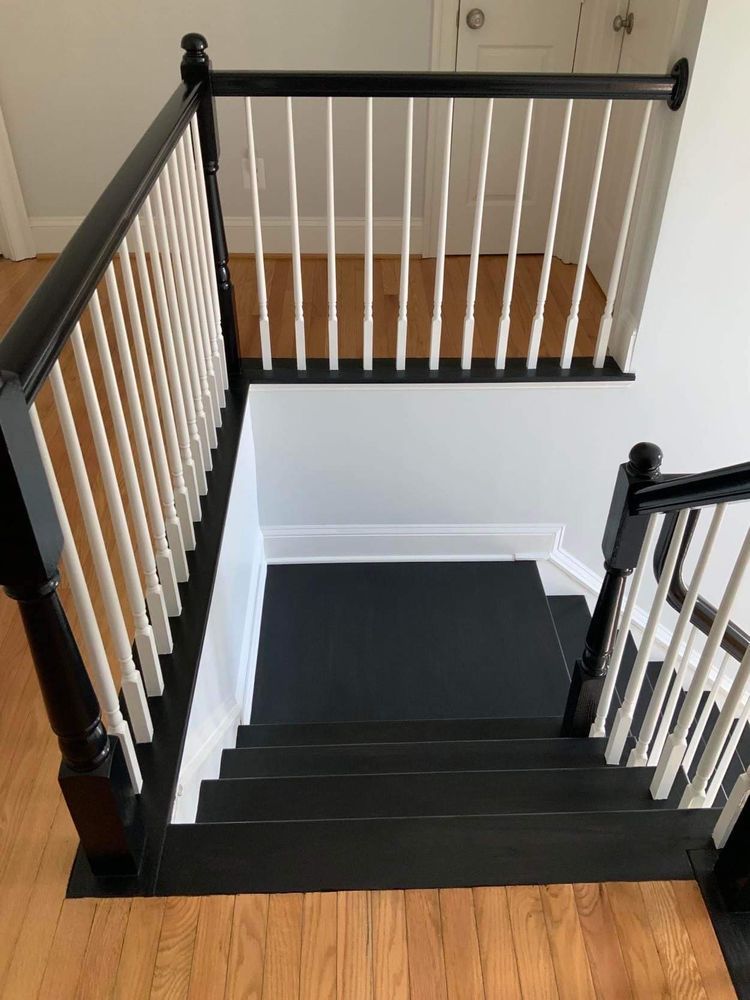 A black staircase with white railings in a house.
