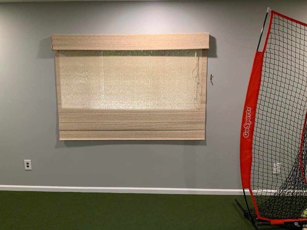 A room with a soccer net and a window with roman shades