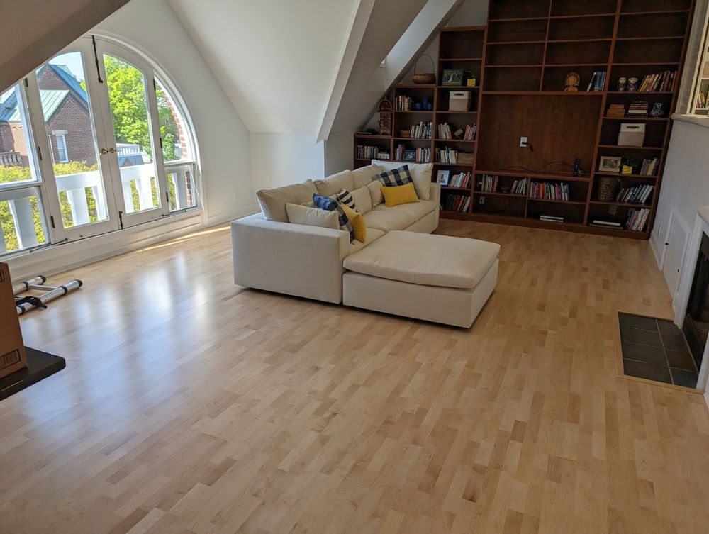 A living room with hardwood floors , a couch , and a fireplace.