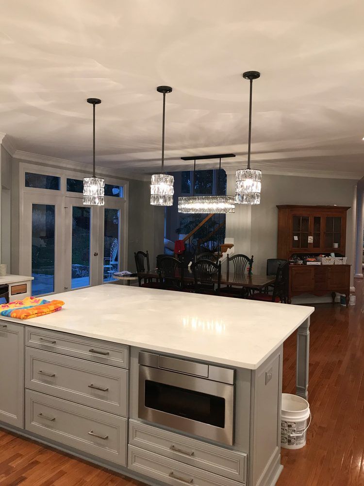 A kitchen with a large island and a stainless steel microwave oven.