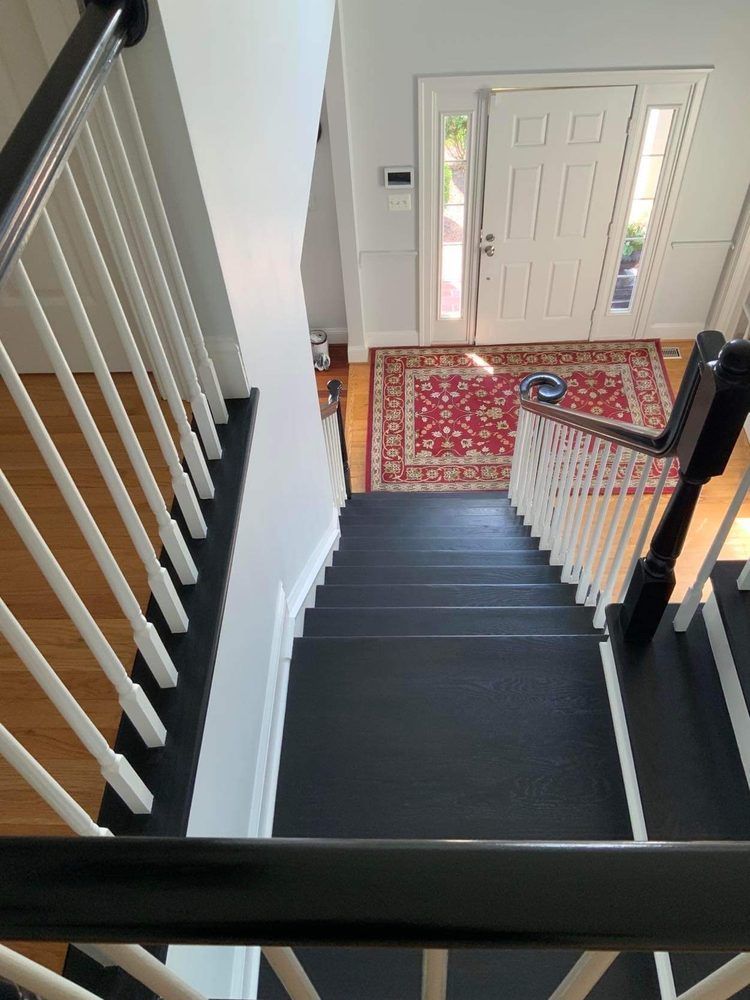 A black staircase with white railings and a red rug in a house.