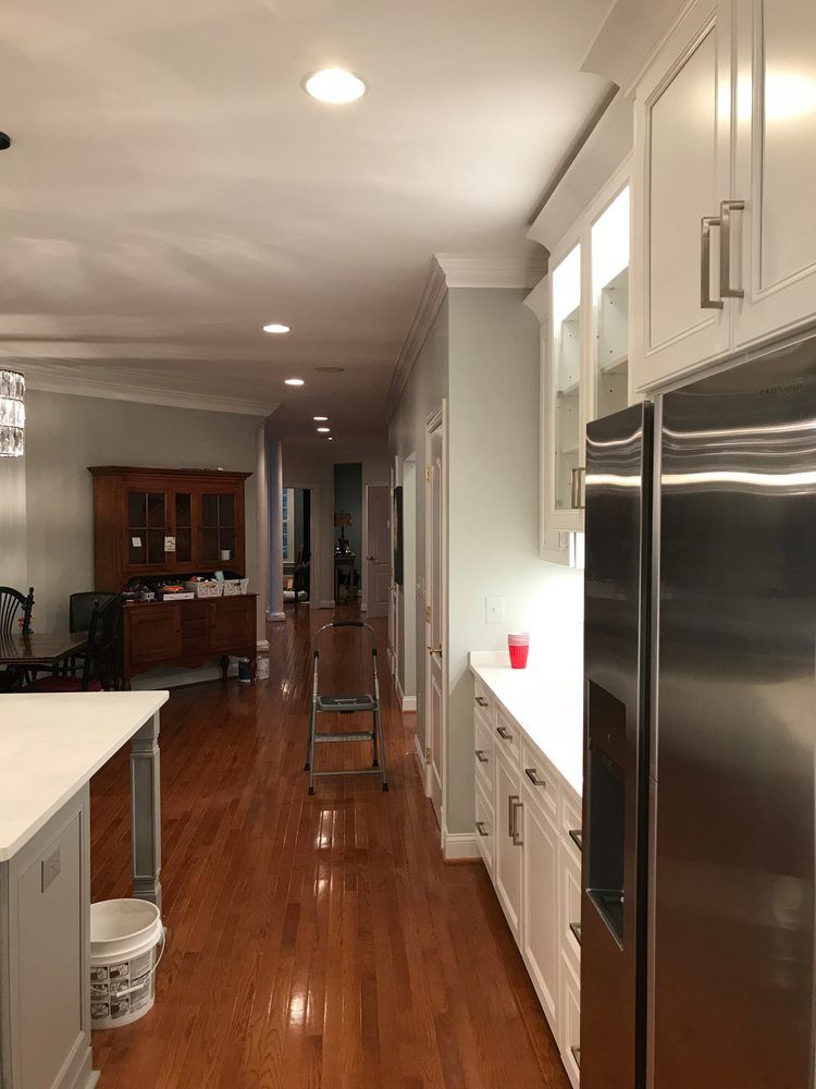 A kitchen with white cabinets and a stainless steel refrigerator.