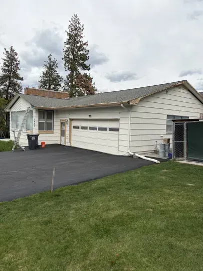 Suburban house with white siding, two-car garage, and a black driveway beside a green lawn