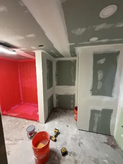 Partially finished room with drywall, red-painted alcove, and paint buckets on the floor