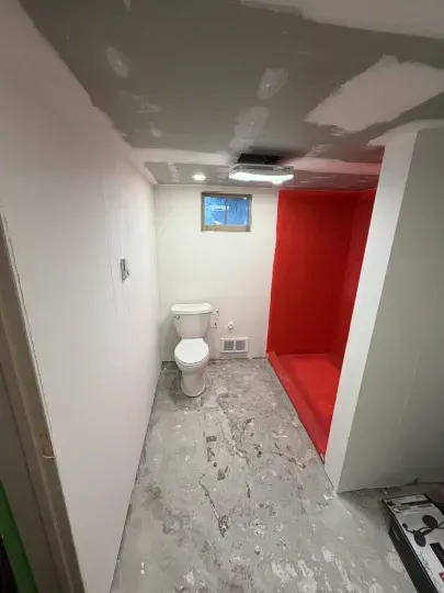 Small bathroom with toilet, gray floor, white walls, and a bright red shower area.