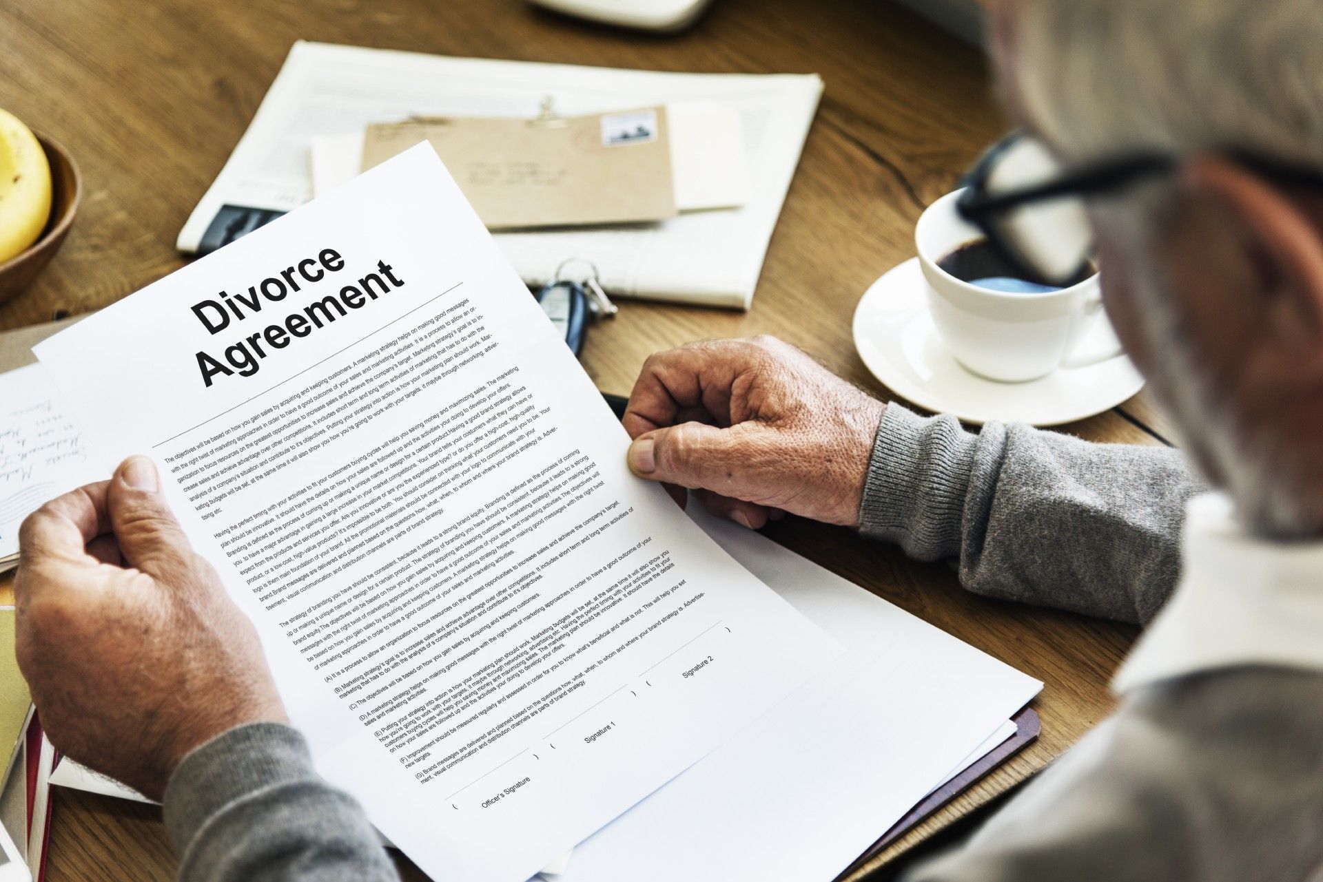 A man is sitting at a table signing a divorce agreement.