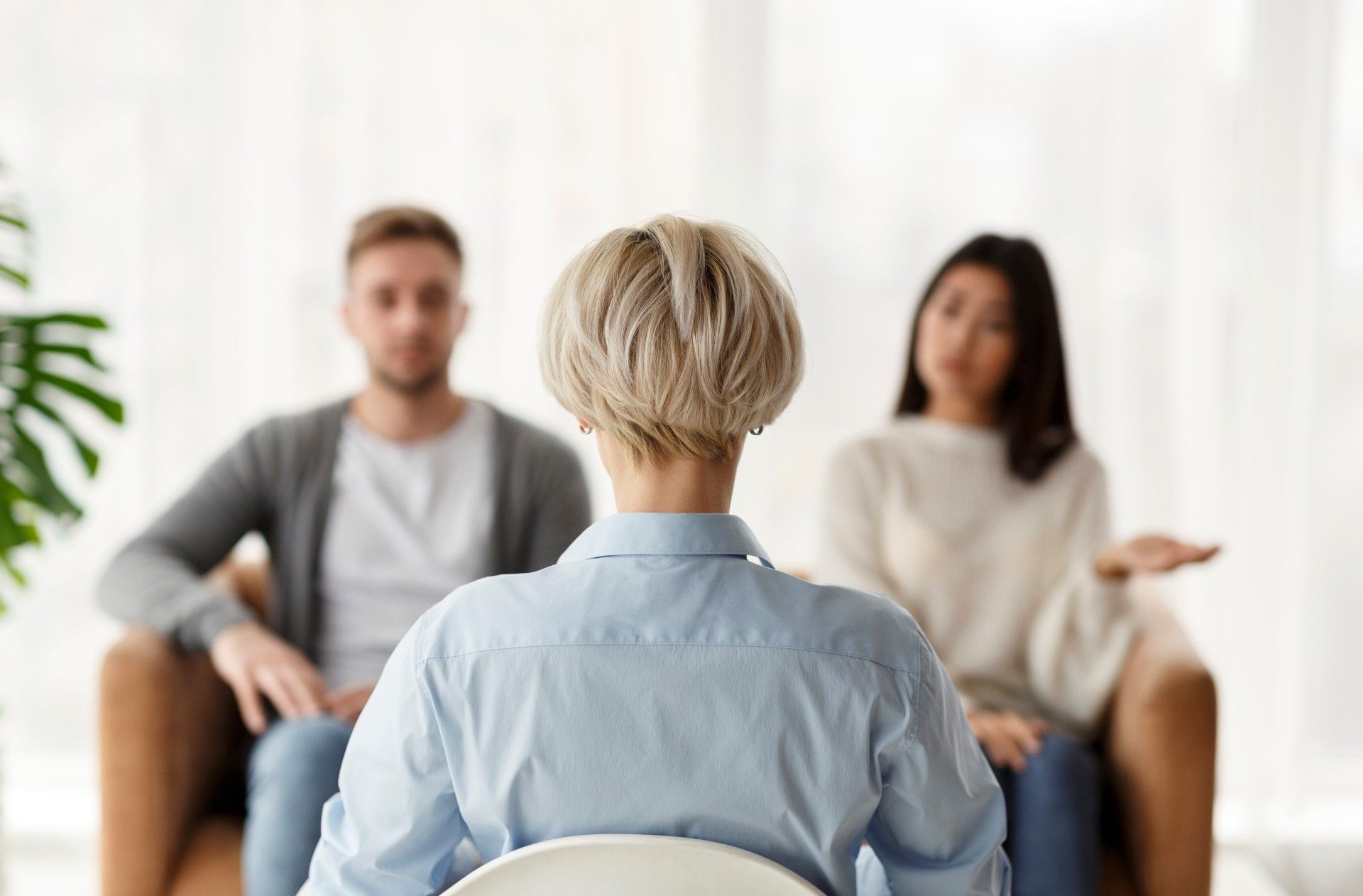 A woman is sitting in a chair talking to a couple.