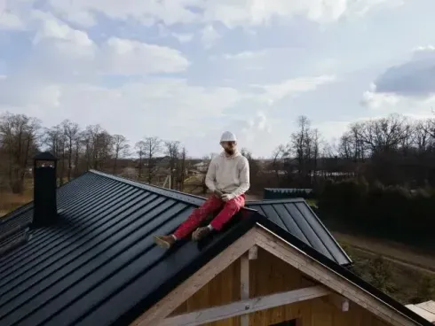Chimney sweep Portland - A man is sitting on the roof of a house.