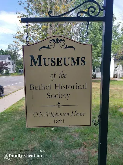Chimney-Sweep-Portland-Metal sign for the Bethel Historical Society's Museums, O'Neil Robinson House, 1821. Set against a street and trees, evoking historical charm.
