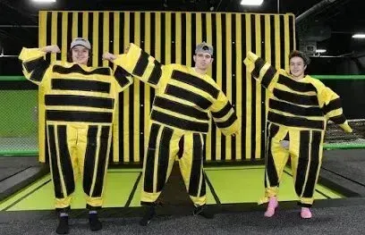 Chimney-Sweep-Portland-A group of people in yellow and black striped jumpsuits are standing next to each other on a trampoline.