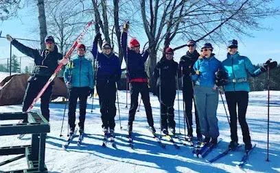 Chimney-Sweep-Portland-A group of eight people in colorful winter gear stands on a snowy landscape, holding ski poles. They smile under a clear blue sky, conveying joy and teamwork.