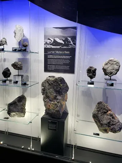 Chimney-Sweep-Portland-Lunar meteorites displayed in illuminated glass cases beneath a sign detailing their origin in a museum exhibit.