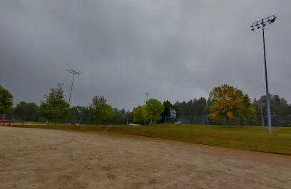 Chimney-Sweep-Portland-Overcast sky over an empty baseball field with a sandy infield and green outfield. Trees with autumn colors surrounding, evoking a calm, serene mood.