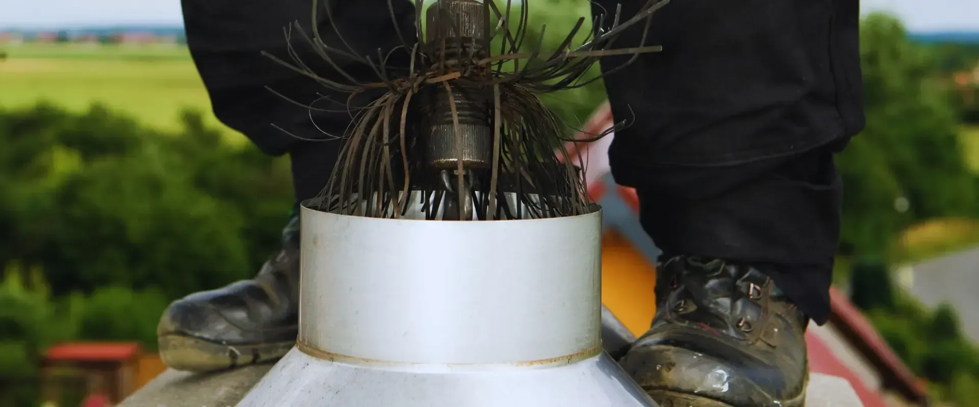A chimney sweep is cleaning a chimney with a brush.