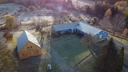 Chimney-Sweep-Portland-Aerial view of a light blue ranch-style house and a wooden barn on a frost-covered rural property.