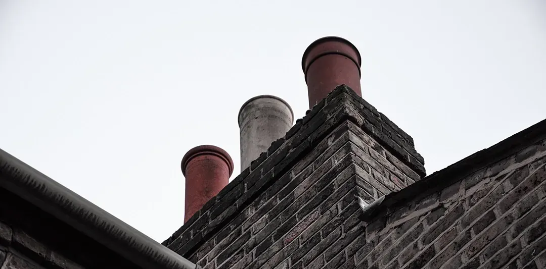 A brick building with three chimneys on top of it.