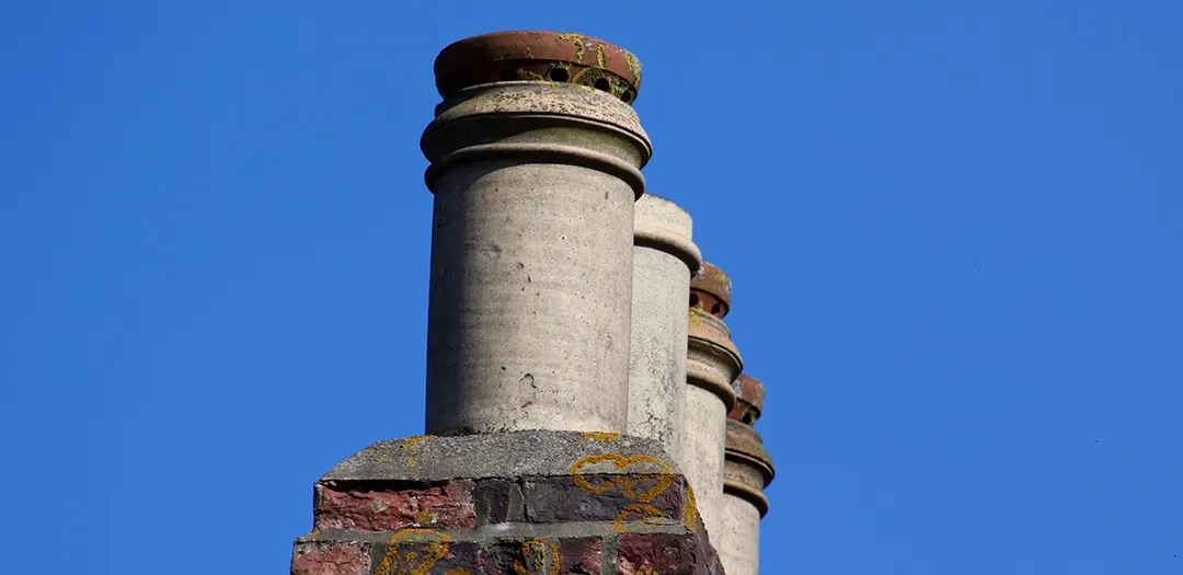 A row of chimneys against a blue sky.