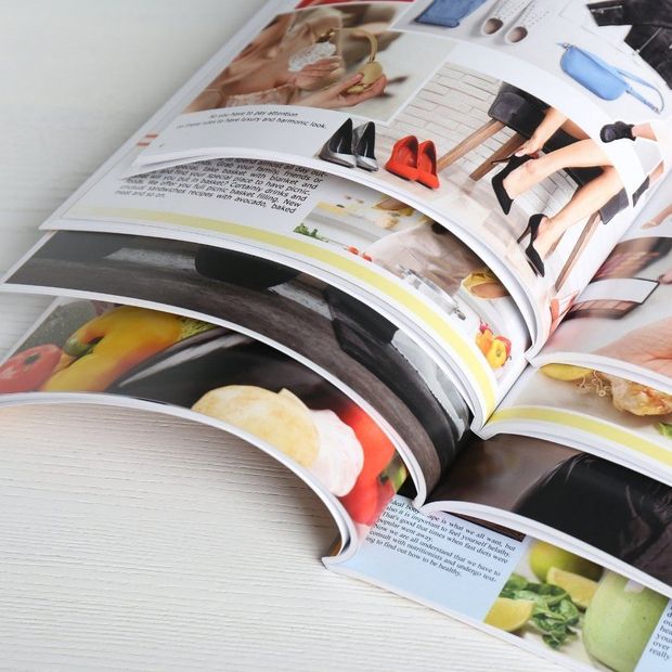Open cookbook with colorful food photos and recipe pages on a white surface