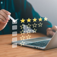 Hand checking a box in a digital customer review with star ratings beside a laptop