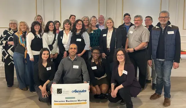 Group of people posing indoors behind an award sign at a professional event.