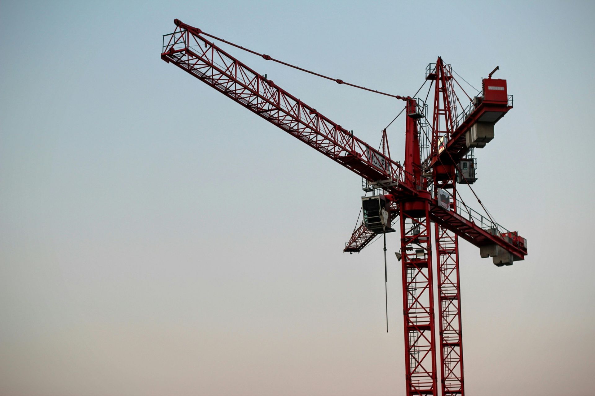 Red construction crane against a dusky sky.