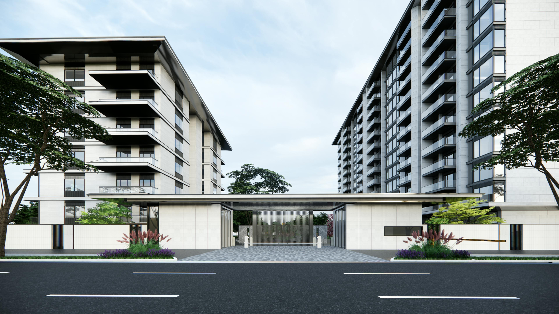 Two modern apartment buildings frame a gated entrance with a street in the foreground under a blue sky.