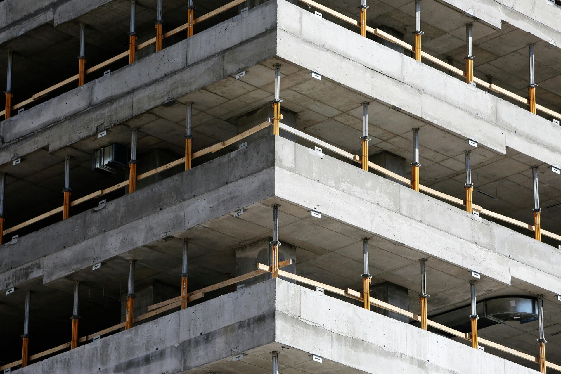 Concrete building under construction, supported by wooden beams and steel posts, outdoors.