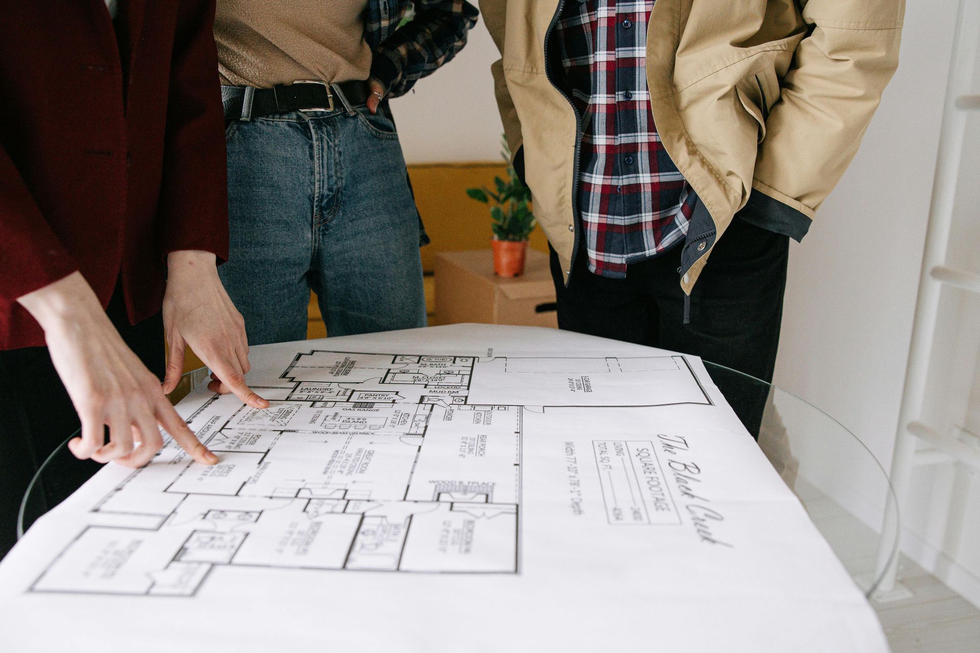 People pointing at a blueprint on a table; planning a project.