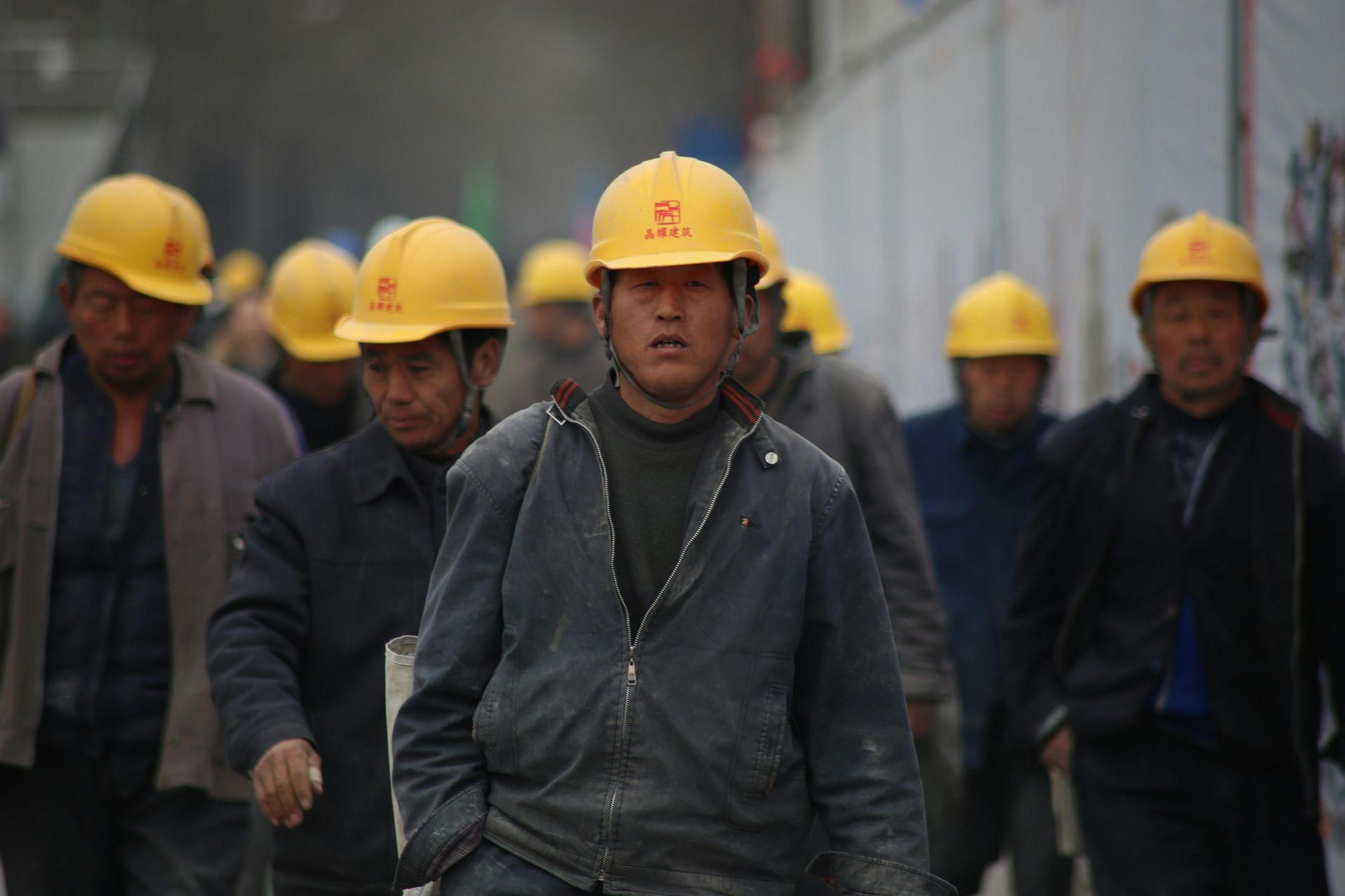 Construction workers wearing yellow helmets walking together, outdoors.