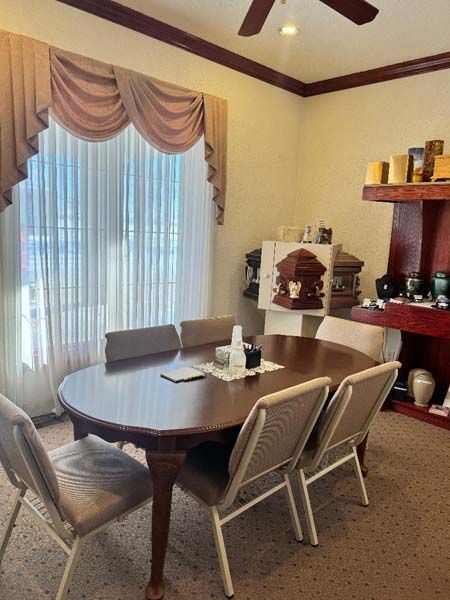 A dining room with an oval table, six chairs, and a window with curtains and a valance.