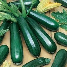 Fresh green zucchini arranged on a wooden surface, some with stems and leaves attached
