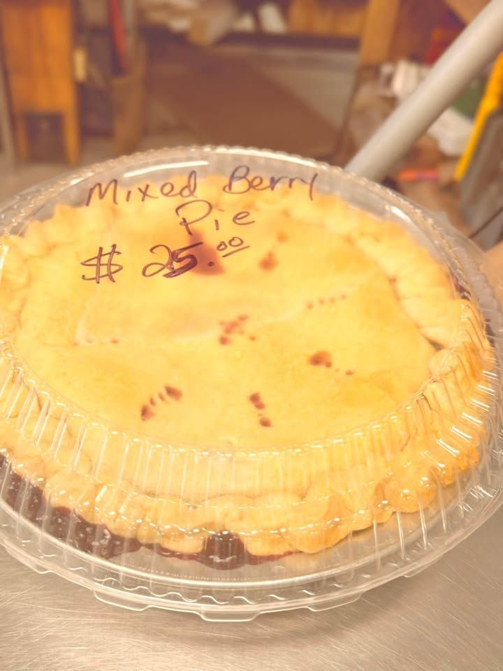Mixed berry pie in a clear plastic container with handwritten label and price.