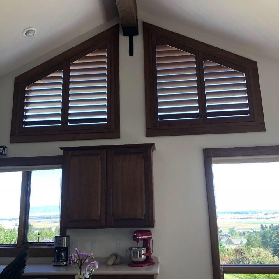 Kitchen with high triangular windows, wooden shutters, cabinets, and a view of the landscape outside