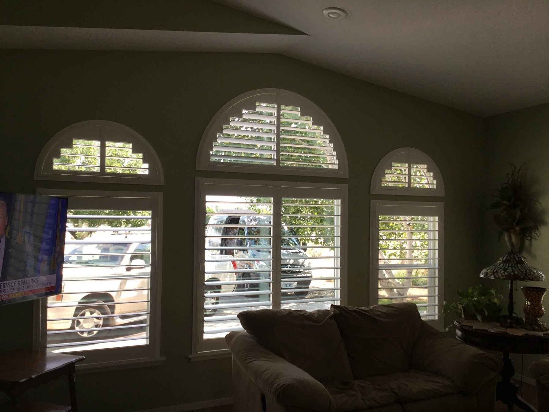 Living room with arched windows, white shutters, and a couch in soft daylight