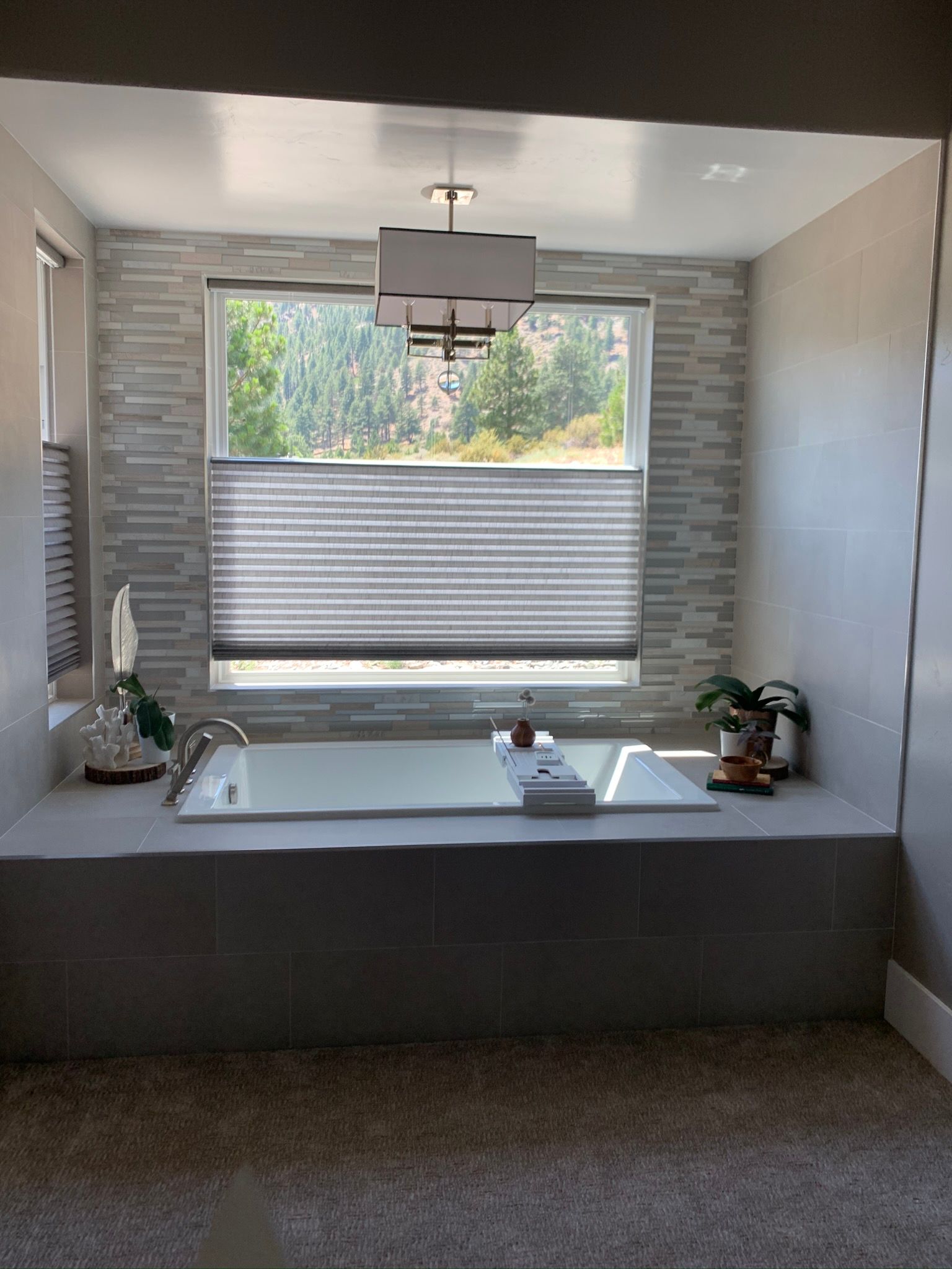 Modern bathroom with a freestanding tub, window, and gray tile walls