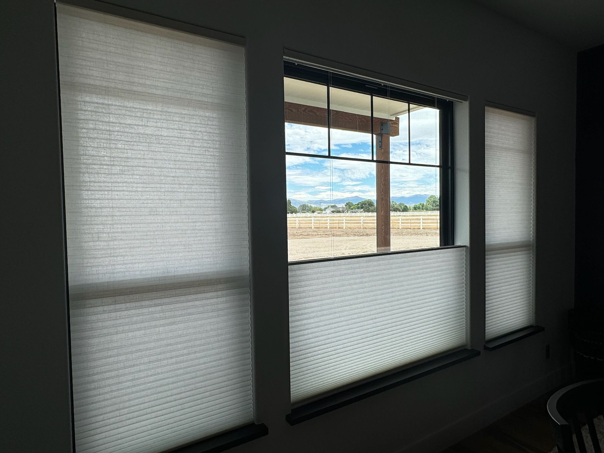 Three tall windows with white blinds, revealing a bright desert landscape outside.