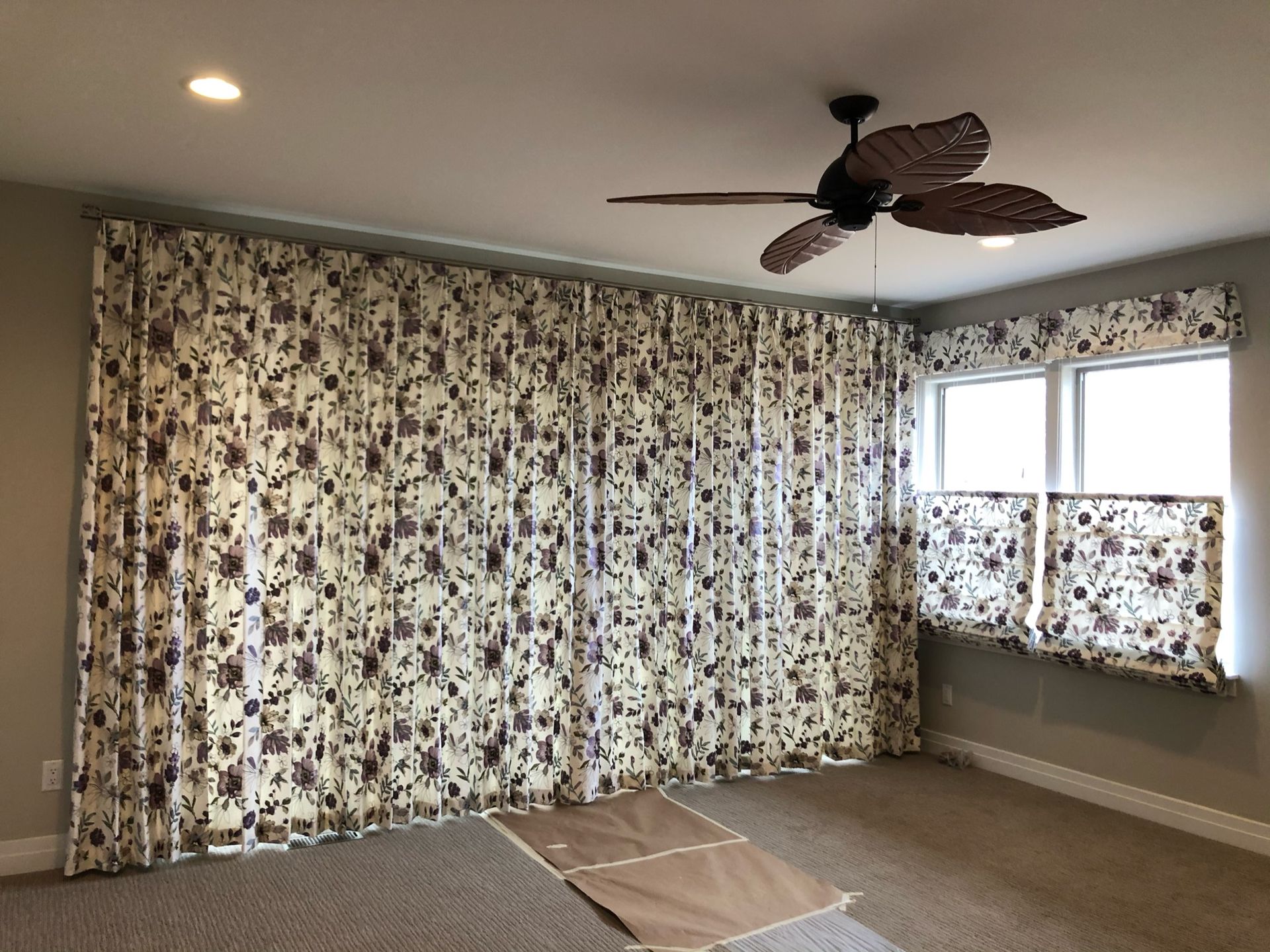 Curtained room with a ceiling fan, window, and carpeted floor in neutral tones