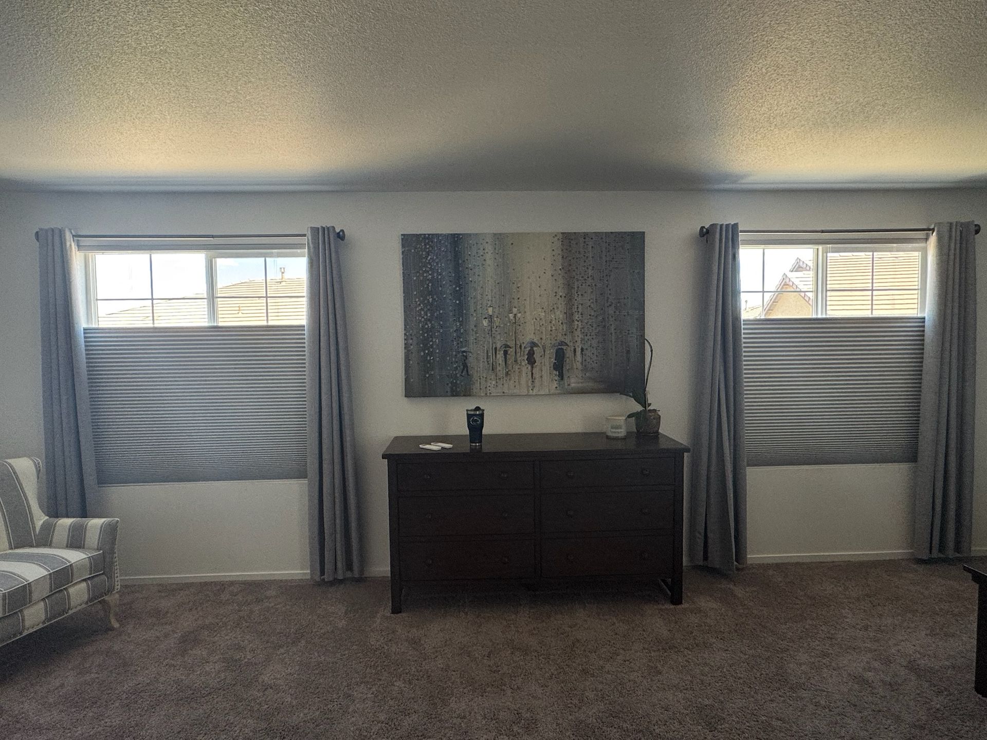 Living room with two windows, a dark dresser, wall art, and gray curtains and carpet