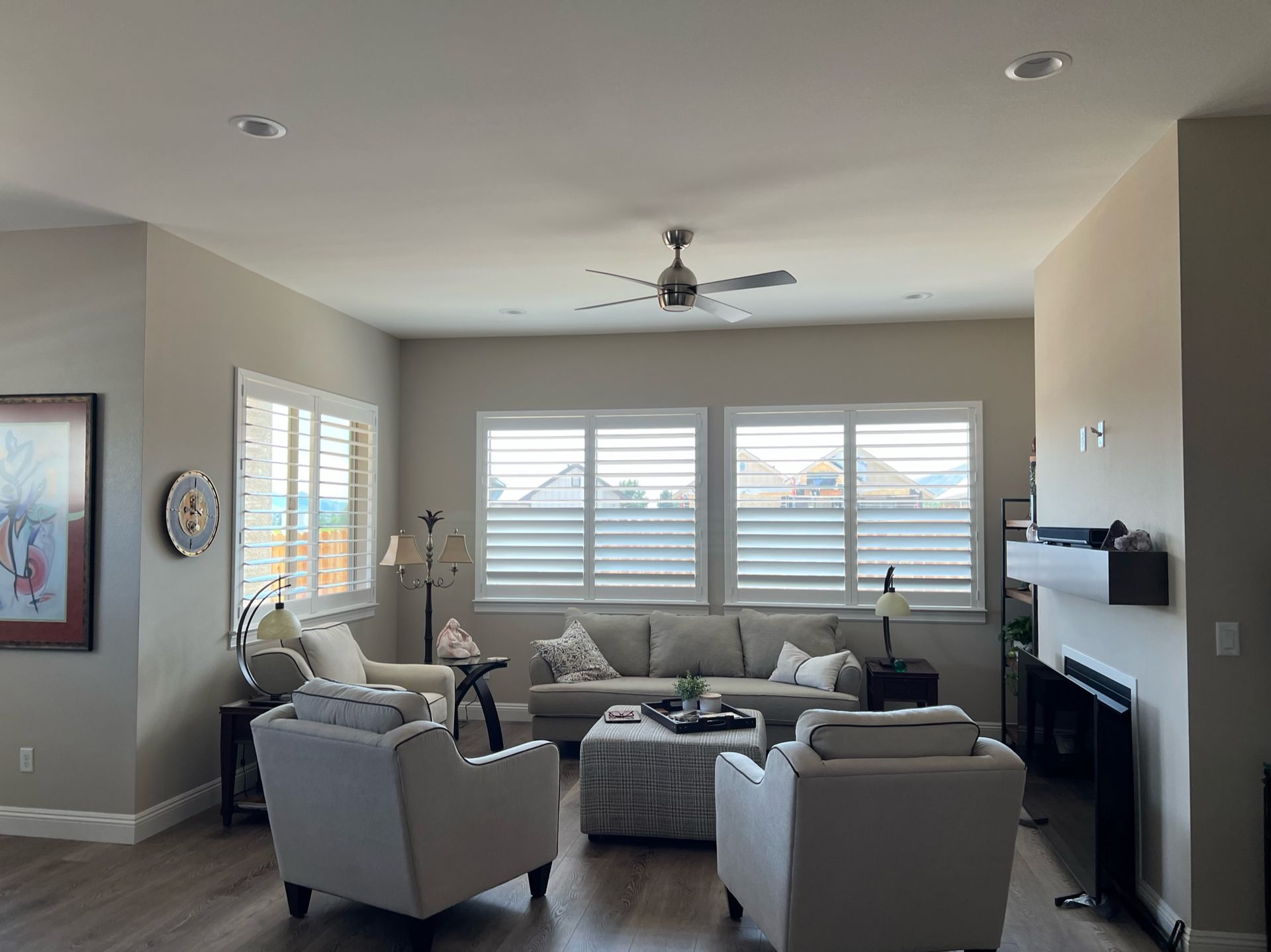 Modern living room with gray sofas, large windows, ceiling fan, and fireplace
